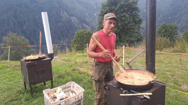 Un socio gira la polenta carbonera nel paiolo all'aperto