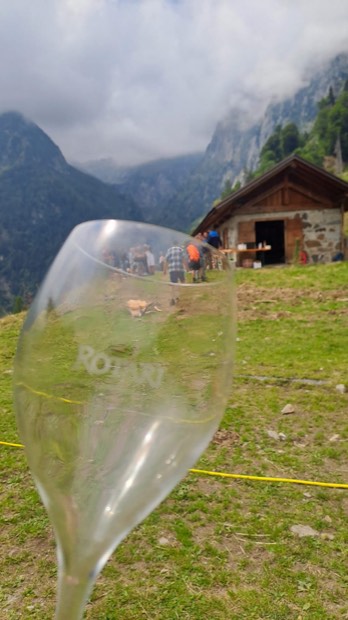 Un calice in primo piano con la malga e i partecipanti sullo sfondo