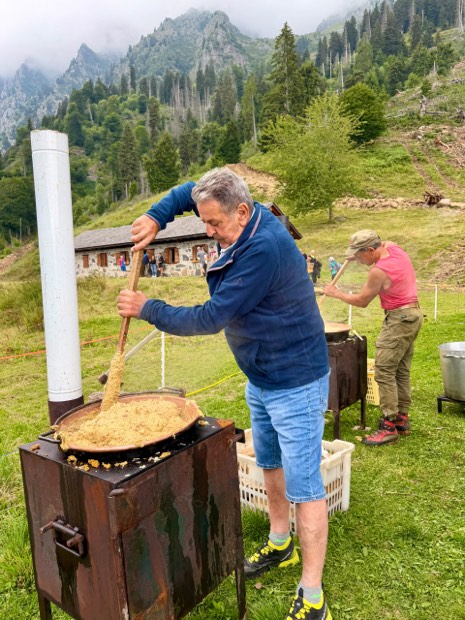 Due soci girano la polenta nei paioli davanti alla malga
