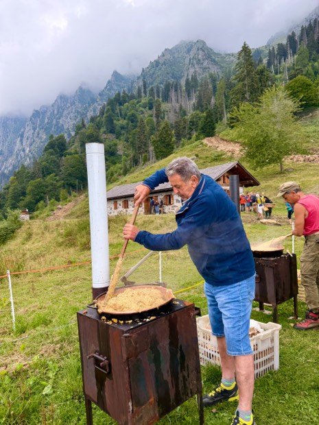 La polenta carbonera girata nel paiolo con la malga sullo sfondo